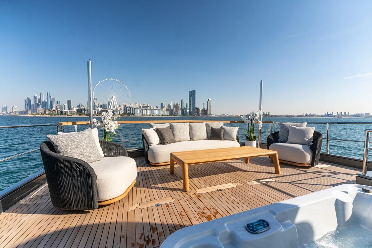 Outdoor lounge chairs and sofa on Spectre’s upper deck with the Dubai waterfront beyond
